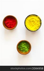 red yellow green holi color powder bowls white background