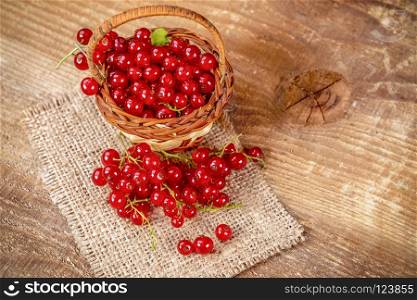 Redcurrant in basket on brown wooden table. Fresh fruits red currant on table.. Redcurrant on wooden table