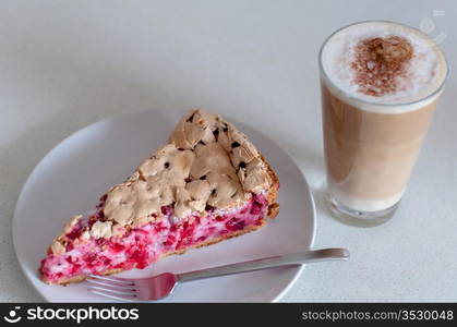 Redcurrant meringue tart on the plate with fork and coffee latte on bright background