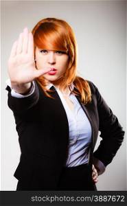 Redhair businesswoman with stop hand sign gesture on gray. Business concept. Studio shot.