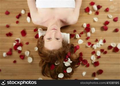Redhead beautiful woman with colorful rose petals on hair