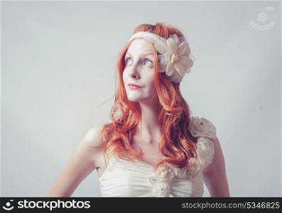 Redhead female looking up. Portrait of a beautiful red haired woman with flower in her hair. Fashion photo