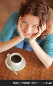 Redhead girl smiling and having a cup of coffee. Indoor shot.