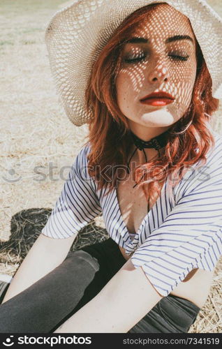  Redhead model protecting herself from sun with a hat in summer                              