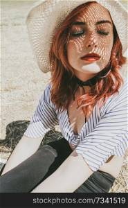  Redhead model protecting herself from sun with a hat in summer                              