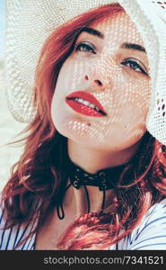 Redhead model protecting herself from sun with a hat in summer                              