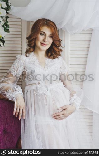 Redhead pregnant girl in a delicate situation.. Portrait of a redhead girl in a transparent negligee 6830.