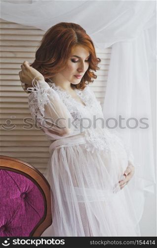 Redhead pregnant girl in a delicate situation.. Portrait of a redhead girl in a transparent negligee 6833.