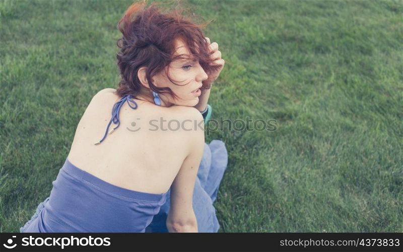redhead sitting on grass, backview, toned image