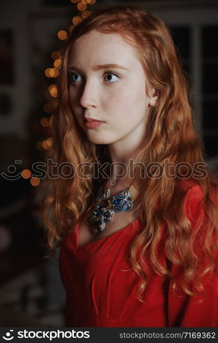 Redhead teenager in a red dress and an ornate necklace