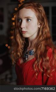 Redhead teenager in a red dress and an ornate necklace