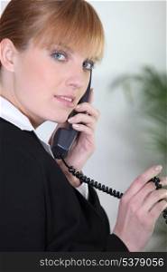 Redhead using an office telephone