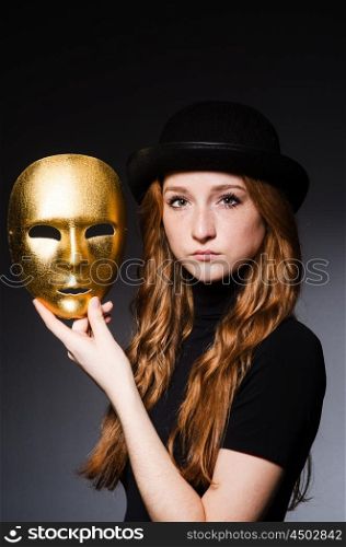 Redhead woman in hat iwith mask in hypocrisy consept against dark grey background
