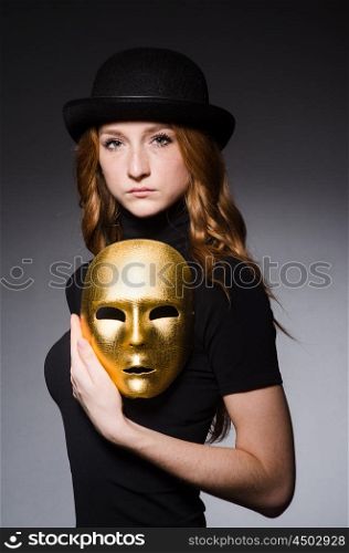 Redhead woman in hat iwith mask in hypocrisy consept against grey background