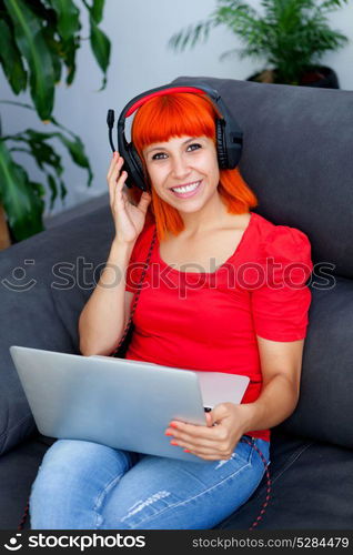 Redhead woman in red listening music with a laptop at home