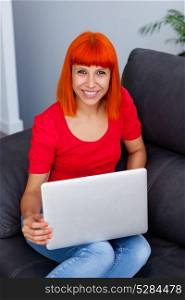 Redhead woman in red with a laptop at home