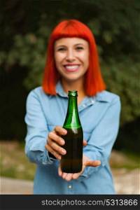 Redhead woman in the countryside toasting with a green bottle in the countryside