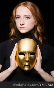 Redhead woman iwith mask in hypocrisy consept against black background