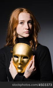 Redhead woman iwith mask in hypocrisy consept against grey background