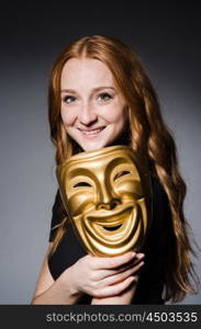 Redhead woman iwith mask in hypocrisy consept against grey background
