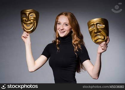 Redhead woman iwith masks in hypocrisy consept against grey background