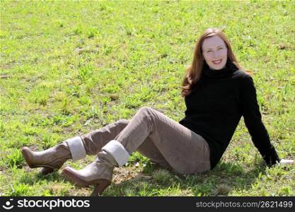 redhead woman sit on meadow grass corduroy pants and boots