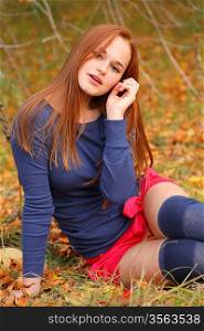 Redhead Woman sitting in the park in autumn
