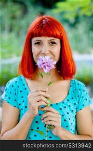 Redhead woman smelling a flower in a beautiful park