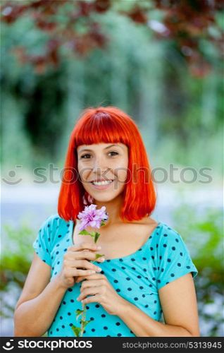 Redhead woman smelling a flower in a beautiful park