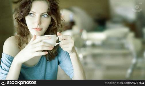 Redhead woman with curly hair drinking coffee from a cup very shallow depth of field