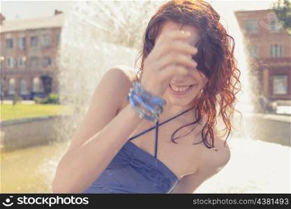 redhead women near fountain in summertime. Shot full og sunshine, Sunlit