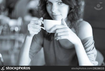 Redhead women sitting in the cafee and holding cup of coffee in the hands looking at camera