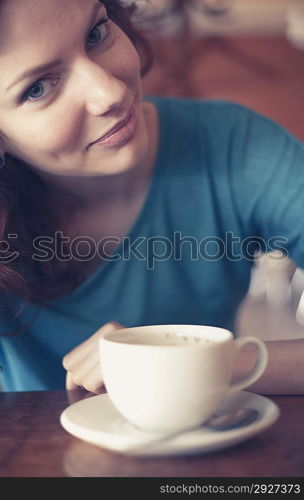 Redhead women sitting in the cafee with cup of coffee on the table befor and looking at camera