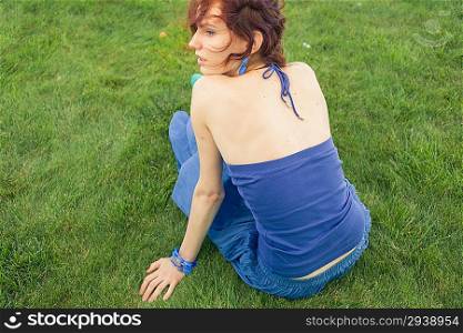 redhead women sitting on the green grass in summertime smiling
