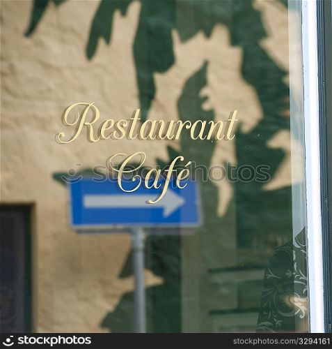 Refelction of arrow street sign in restaurant window