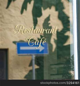 Refelction of arrow street sign in restaurant window