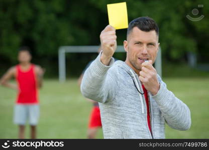 referee on football field showing yellow card