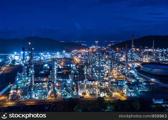 refinery oil and gas storage production industry and mountain with blue sky background at night over lighting aerial view in Thailand