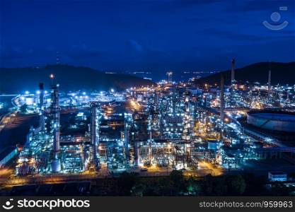 refinery oil and gas storage production industry and mountain with blue sky background at night over lighting aerial view in Thailand