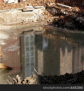 Reflection in an excavation pit with groundwater on which a thick, greasy layer of heating oil floats, germany