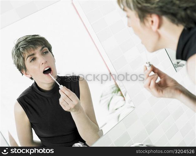 Reflection of a mature woman applying lipstick
