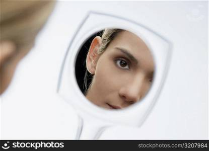 Reflection of a young woman&acute;s face in a vanity mirror
