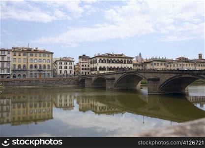 Reflection of an arch bridge in water, Ponte Santa Trinita Bridge, Arno River, Florence, Italy