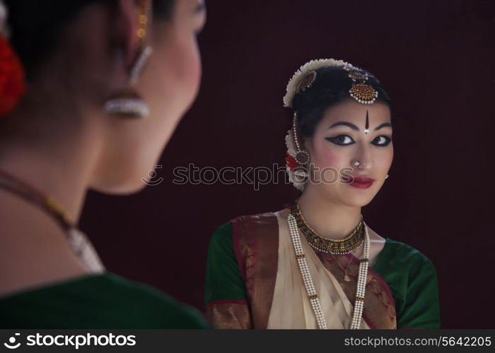 Reflection of beautiful Bharatanatyam dancer in mirror over black background