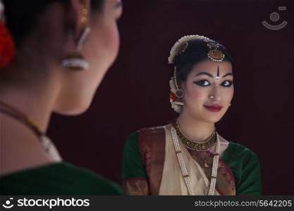 Reflection of beautiful Bharatanatyam dancer in mirror over black background