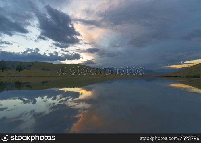 Reflection of blue and yellow clouds on the water Drakensberg South Africa