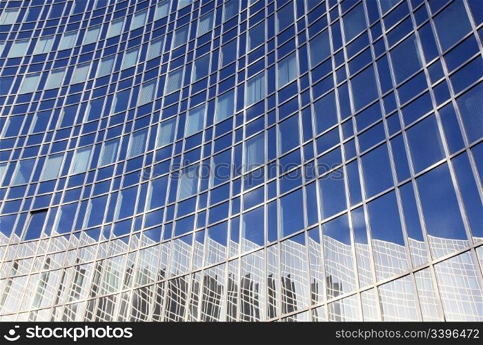 reflection of blue sky and building in curved facade