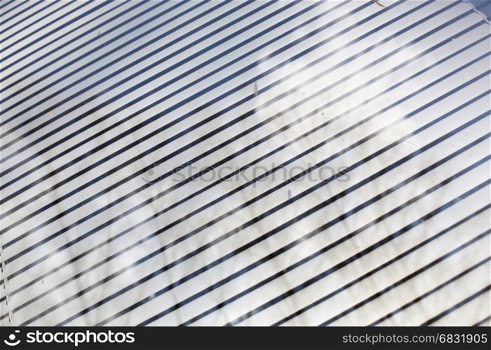 Reflection of clouds and trees in the window with blinds