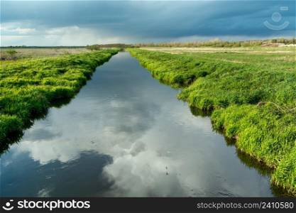 Reflection of clouds in a calm river with a green bank, Czulczyce, Lubelskie, Poland
