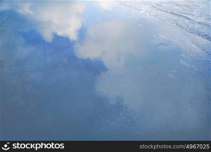 Reflection of clouds in waves at the beach